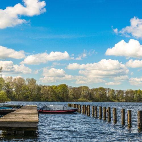 Sea With Boats Near Dock Green Trees Distance Blue Sky