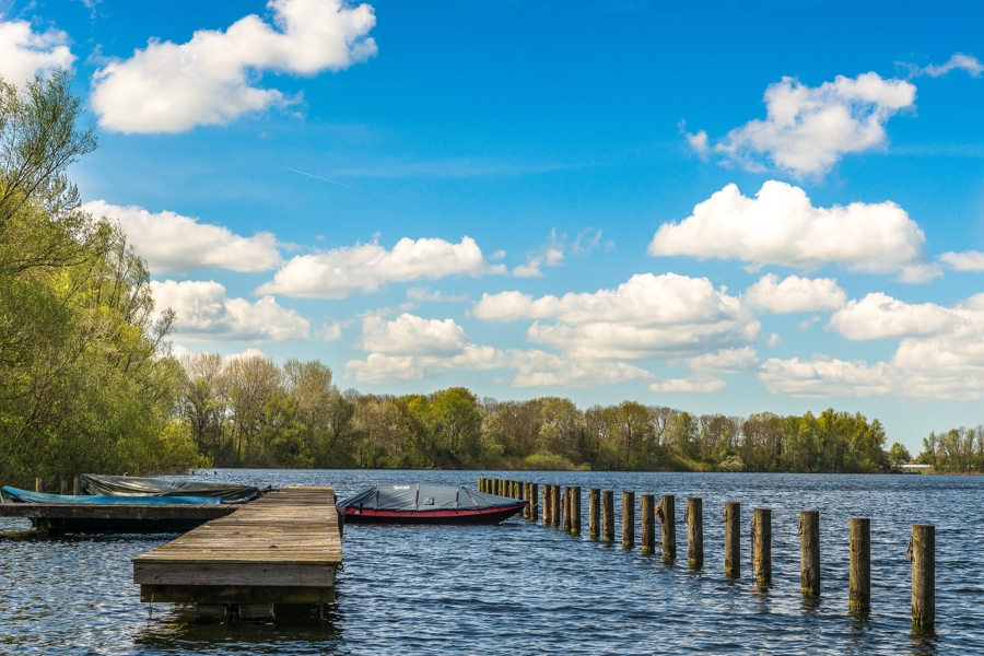 Sea With Boats Near Dock Green Trees Distance Blue Sky